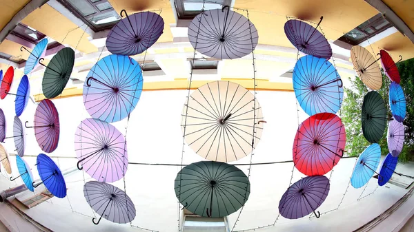 Barevné Dekorativní deštníky visí mezi budovami jako prot — Stock fotografie