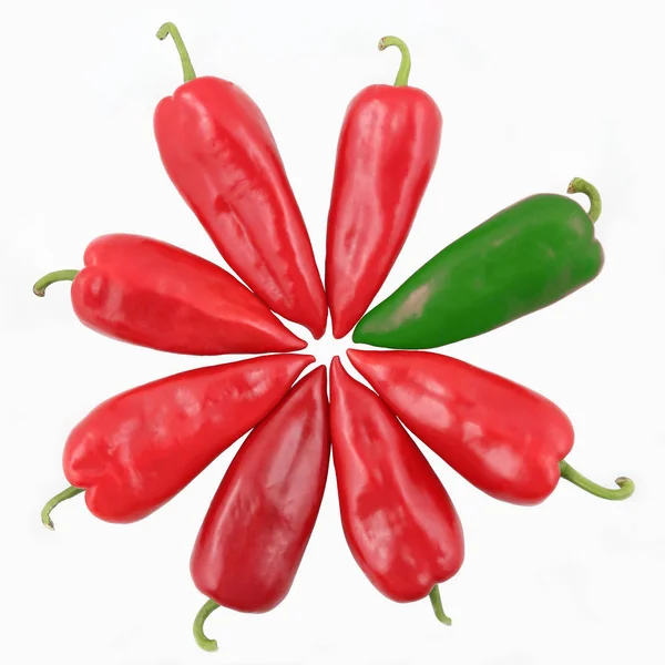 One green and seven red sweet peppers on a white background — Stock Photo, Image