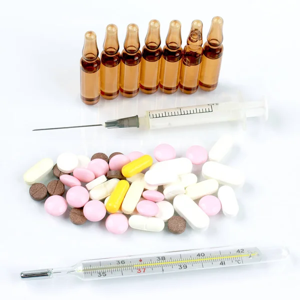 Comprimidos medicinales, ampollas inyectables, termómetro, jeringa — Foto de Stock