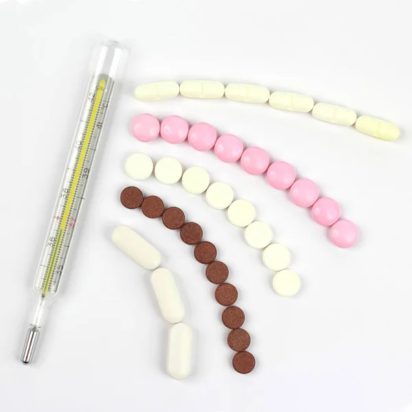 Thermometer und medizinische Pillen auf weißem Hintergrund — Stockfoto