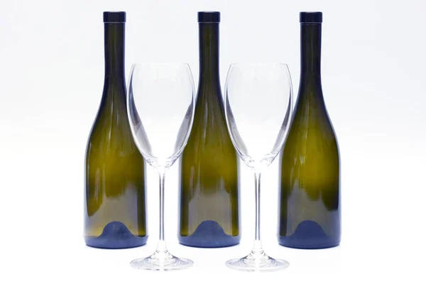 Три порожні пляшки вина та дві склянки на білому спині — стокове фото