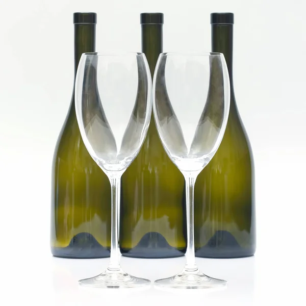 Three empty wine bottles and two glasses on a white background.