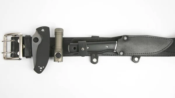 Dva nože a baterka připojená k černým koženým páskem — Stock fotografie