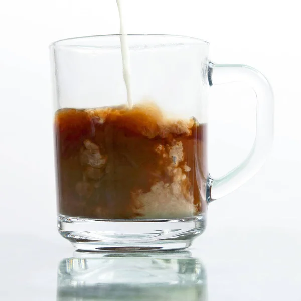 Leche vertida en una taza transparente de café negro —  Fotos de Stock