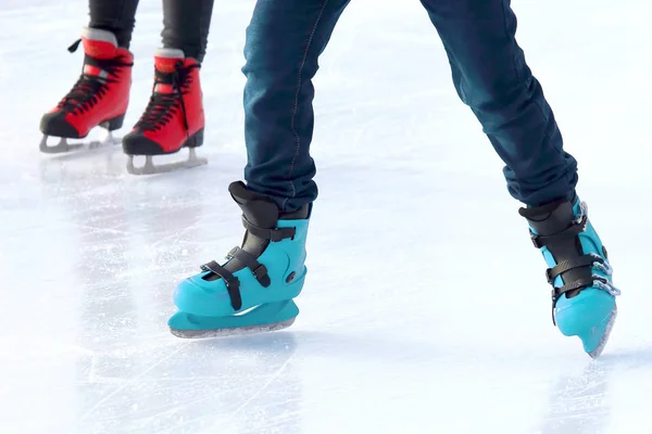 Füße verschiedener Menschen, die auf der Eisbahn Schlittschuh laufen — Stockfoto