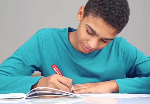 Adolescente de blusa azul escreve em uma lição de caderno — Fotografia de Stock