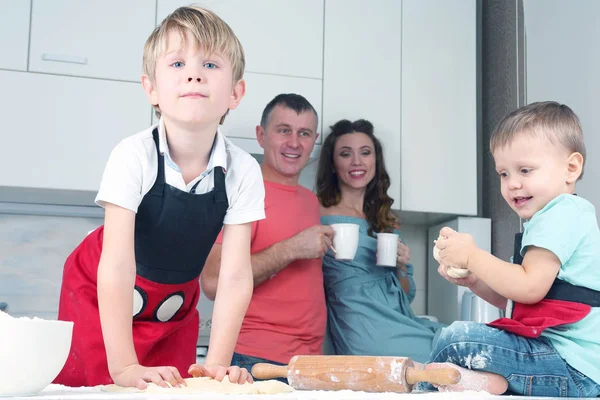 little boys knead the dough on the background of their parent
