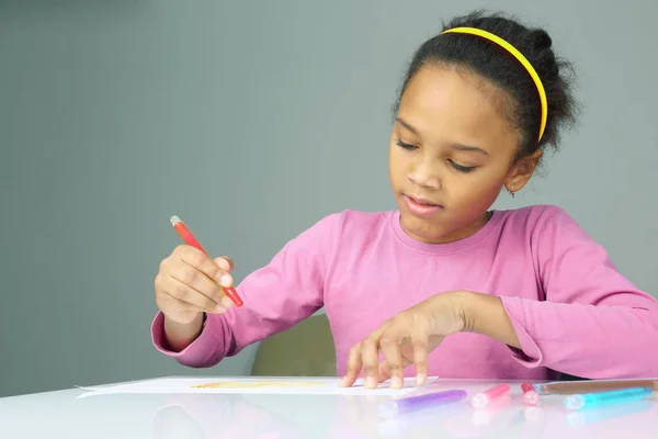 A menina desenha um lápis vermelho no papel branco — Fotografia de Stock
