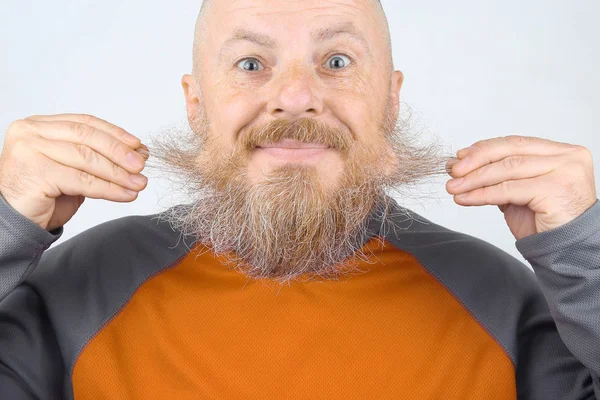 Bald, bearded, smiling man touching his beard