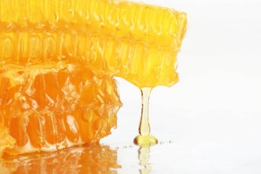 hafif bir arka plan üzerinde peteğin üzerinden akan bal