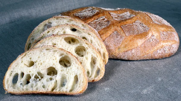 Φέτες άσπρο ψωμί, που βρίσκεται σε άχυρα στην γκρίζα τραπεζομάντιλο λινού — Φωτογραφία Αρχείου