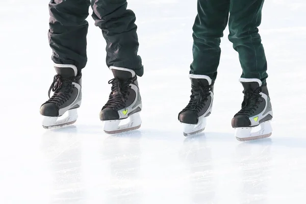 Pés de pessoas diferentes patinando na pista de gelo — Fotografia de Stock