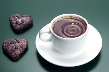 Beyaz ile bisküvi karanlık bir arka plan üzerinde siyah kahve fincan