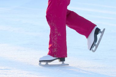 Buz pateni pistinde yuvarlanan birinin ayakları.