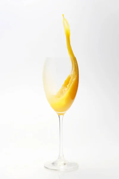 Respingo de suco de laranja no vidro no fundo branco — Fotografia de Stock