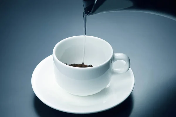 El agua hervida se vierte en una taza blanca con café negro — Foto de Stock