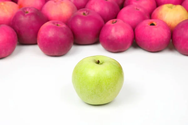 Maçã verde em um fundo de maçãs vermelhas em fundo branco — Fotografia de Stock
