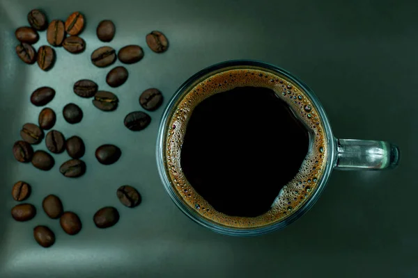Чашка черного кофе на коричневой тарелке с кофейными зёрнами — стоковое фото