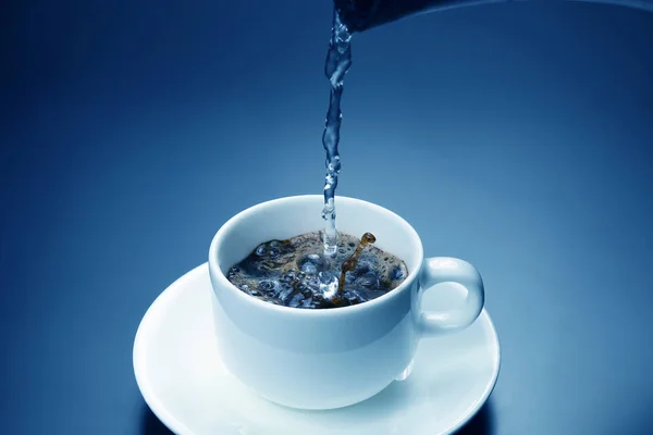 El agua hervida se vierte en una taza blanca con café negro — Foto de Stock