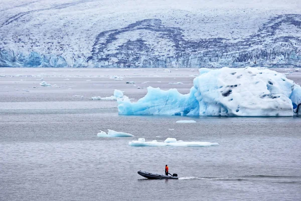 Man på en snabb motorbåt som seglar på en glaciärlagun på Island — Stockfoto