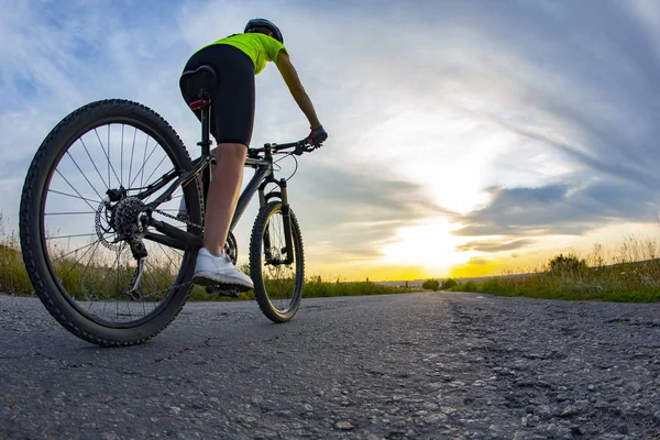 Mooi meisje fietser rijdt een fiets op de weg in de zonsondergang — Stockfoto