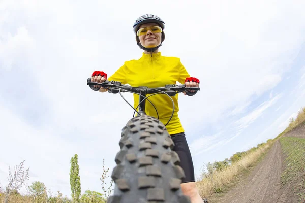 Schöne Radfahrerin mit einem Fahrrad auf einem Himmelshintergrund. heilen — Stockfoto