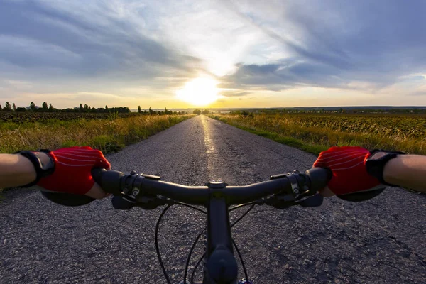 Handen op het stuurwiel rijden een fietser op de weg naar — Stockfoto