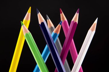 Koyu bir arkaplana çizim yapmak için renkli kalemler. Eğitim ve 