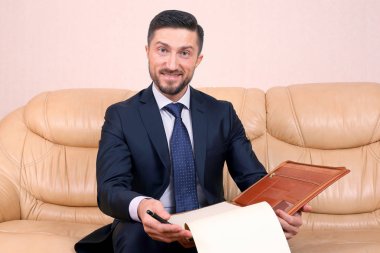 Başarılı bir iş adamı üzerine oturduğu iş belgeleriyle meşgul.