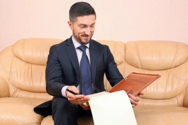 Başarılı bir iş adamı üzerine oturduğu iş belgeleriyle meşgul.