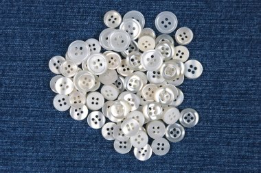 Kumaş arka plandaki kıyafetler için plastik parlak düğmeler. Moda ve giysi. Fabrika endüstrisi