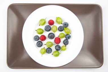 Beyaz tabakta çeşitli taze meyveler var. Sağlıklı meyve vitamini. sağlıklı sebze kahvaltısı