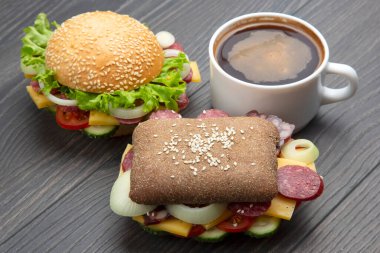 Sebzeli hamburger, sosis ve gri arka planda kahve. Fast food ve kahvaltı. Kalori ve diyet.