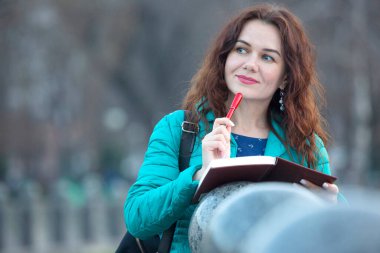 Elinde kırmızı kalemle gülümseyen güzel bir kızın portresi.