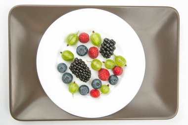 Beyaz tabakta çeşitli taze meyveler var. Sağlıklı meyve vitamini. sağlıklı sebze kahvaltıları