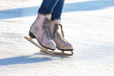 Mavi kotlu ve buz pistinde beyaz patenli bir kızın bacakları. Hobiler ve boş vakitler. kış sporu