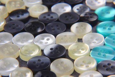 Kumaş arka plandaki kıyafetler için plastik parlak düğmeler. Moda ve giysi. Fabrika endüstrisi