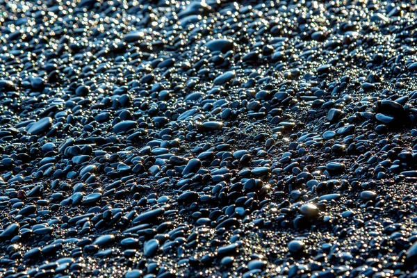 wet dark pebbles and rocks on the ocean coast