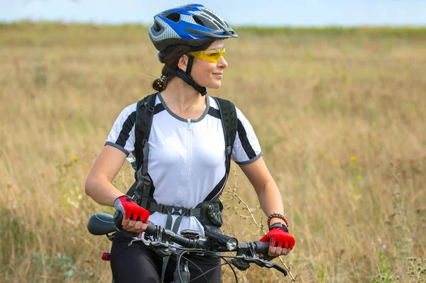 Beautiful and happy girl cyclist with a bike on nature. Healthy lifestyle and sports. Leisure and hobbie