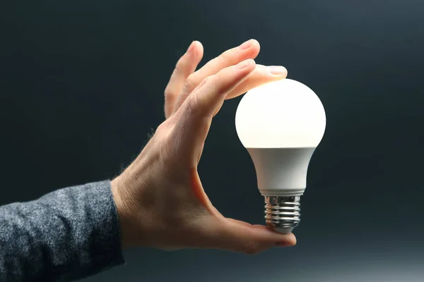 human hand holding the included led lamp on a dark background. electricity and LED industry