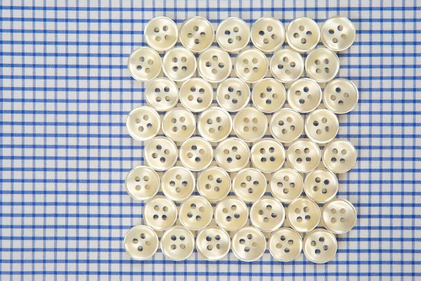 Plastic shiny buttons for clothes on a fabric background. Fashion and clothing. Factory industry