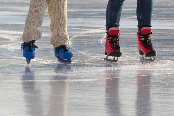 feet of different people skating on the ice rink. hobbies and leisure. winter sports