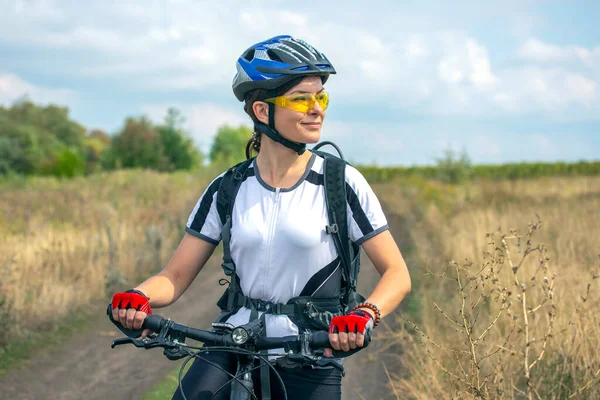 Beautiful and happy girl cyclist with a bike on nature. Healthy lifestyle and sports. Leisure and hobbie