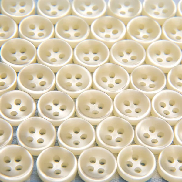 Plastic shiny buttons for clothes on a fabric background. Fashion and clothing. Factory industry