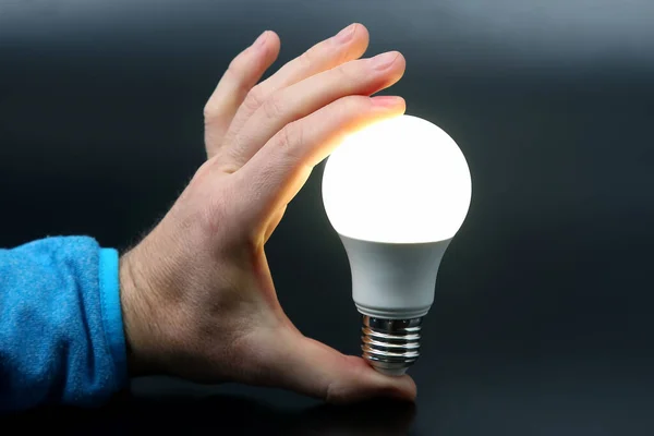 human hand holding the included led lamp on a dark background. electricity and LED industr