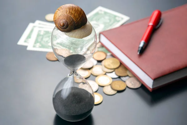 snail crawls on an hourglass against the background of money. speed and stability in increasing income. time for work and rest. financial business success. time investment target