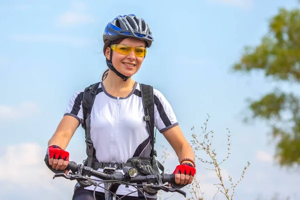 Beautiful and happy girl cyclist with a bike on nature. Healthy lifestyle and sports. Leisure and hobbies