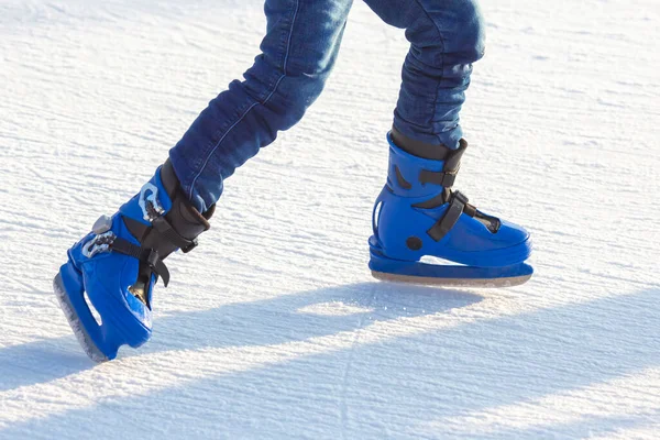 legs of a man in blue skates rides on an ice rink. hobbies and leisure. winter sports