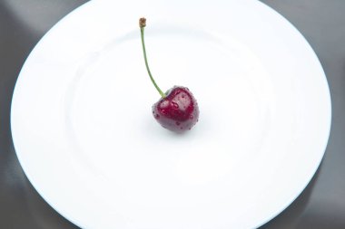 Sulu kiraz böğürtlenleri beyaz bir tabakta yatıyor. Kahvaltıda sağlıklı yemek. Bitkilerin meyveleri. meyve tatlısı