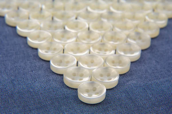 Plastic shiny buttons for clothes on a fabric background. Fashion and clothing. Factory industry